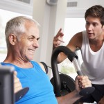 Middle Aged Man Being Encouraged By Personal Trainer In Gym